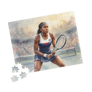 May include: A watercolour jigsaw puzzle depicting a tennis player in a navy and white tennis outfit, holding a racket. The puzzle shows the player on a tennis court with a crowd in the background. The New Balance logo is visible.