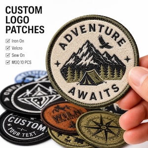 Puede incluir: Un parche bordado circular que muestra una cadena montañosa, una tienda de campaña y un pájaro volando con el texto ADVENTURE AWAITS. El parche tiene un fondo beige y un borde verde oscuro. A la izquierda dice CUSTOM LOGO PATCHES, Iron On, Velcro, Sew On, MOQ 10 PCS.