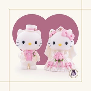 May include: Two Hello Kitty figurines dressed for a wedding. The left figure wears a white top hat, a white jacket, and a pink vest with a bow tie. The right figure wears a white dress with pink bows, a pink rose bouquet, and a white veil with a tiara.