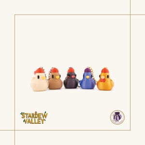 May include: Five colorful chicken-shaped keychains. Each keychain is a different color: cream, brown, dark purple, blue, and yellow. Each chicken has a red or purple hat and a gold chain. The text "Stardew Valley" is visible in the lower left corner.