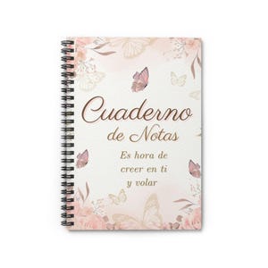 Puede incluir: Cuaderno de espiral con una cubierta con un diseño de mariposas y flores en tonos rosas y beige. La cubierta incluye el texto en español "Cuaderno de Notas" y la frase inspiradora "Es hora de creer en ti y volar."