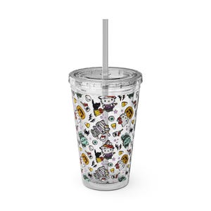 Puede incluir: Un vaso de plástico transparente con tapa y pajita que presenta un patrón repetitivo de temática de Halloween con Hello Kitty vestida de bruja y momia, gatos negros, calabazas, dulces, globos oculares, calaveras y rayos sobre fondo blanco.