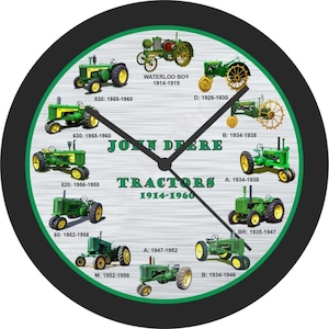 May include: A circular wall clock with a black surround and a green and white face. The clock face displays illustrations of John Deere tractors from 1914-1960, with the brand name and the word "Tractors" clearly visible.