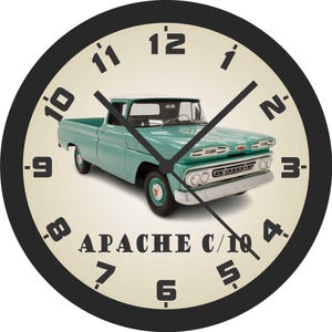 May include: Round wall clock with a black bezel and a cream-colored face. The clock features a teal vintage pickup truck in the center, with the text "APACHE C/10" below. Black hands indicate the time.