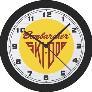 May include: Round wall clock with a black frame and a white face. The clock features black hands and a yellow centre with the words "Bombardier SKI-DOO" in maroon. Numbers are in black.