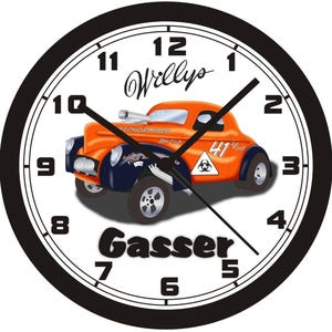 Könnte beinhalten: Eine runde Wanduhr mit schwarzem Rahmen und weißem Zifferblatt mit schwarzen Zahlen. In der Mitte befindet sich eine Illustration eines orangefarbenen und dunkelblauen Willys Gasser Rennwagens mit dem Text Willys und Gasser, der Nummer 41 und einem Biohazard-Symbol.