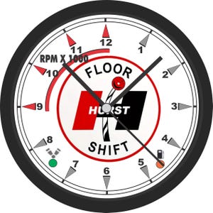May include: A round clock face with a black bezel and white background. The clock features the text "FLOOR SHIFT HURST" in a red and black logo. The clock hands point to 10:08. The clock also has an RPM gauge and fuel gauge.