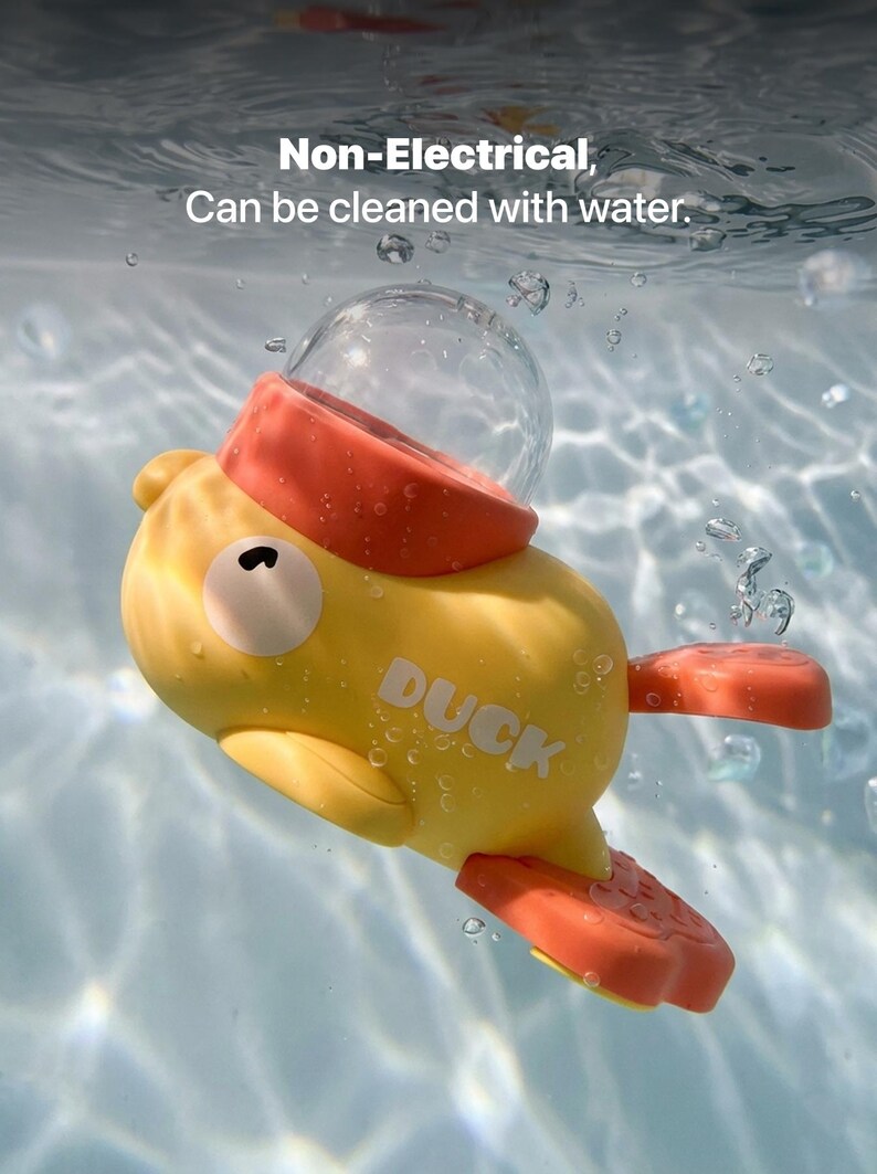 May include: A yellow toy duck with orange accents floats in water. The duck has a clear bubble on top and the word "DUCK" printed on its side. The text "Non-Electrical, Can be cleaned with water" is visible in the background.