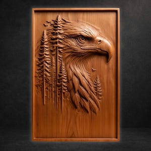 May include: A detailed wood carving of an eagle's head and part of its body, with a forest scene incorporated into the design. The artwork is framed in a rectangular shape and is made of a warm, brown wood.