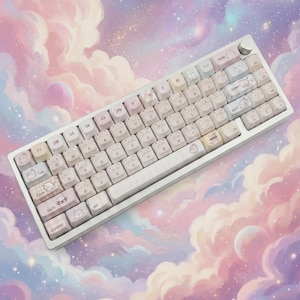 Pode incluir: Um teclado mecânico branco com teclas em tons pastel com ilustrações de gatos. O teclado tem uma estrutura prateada e um botão de volume. O fundo é uma ilustração sonhadora de nuvens, planetas e estrelas.