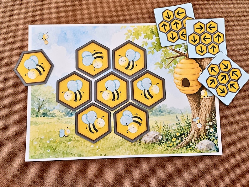 May include: A rectangular game board featuring a meadow scene with a tree and beehive, accompanied by seven hexagonal tiles depicting cartoon bees and three square tiles displaying yellow honeycomb patterns with black directional arrows.