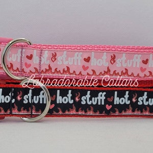 May include: Two dog collars, one pink and one red, with a black and white flame and heart pattern. The collars have the text "hot stuff" on them. Labradorable Collars is printed on the pink collar.