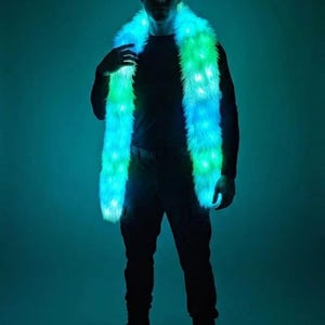 May include: A long, plush faux fur scarf featuring integrated LED lights that emit a vibrant glow in shades of blue and green. The scarf is draped around the neck, with the soft, textured material illuminated by multiple light points throughout.