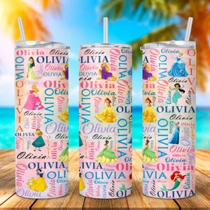 May include: Three pink insulated tumblers with princess illustrations and the name "Olivia" repeated in a pattern. Each tumbler has a white straw. The background shows a beach scene with palm trees.