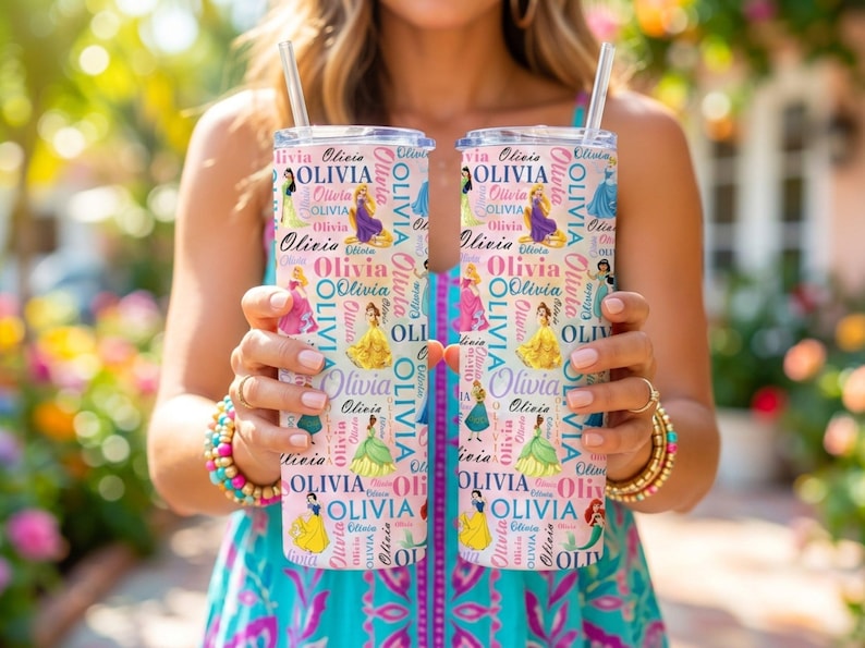 May include: Two personalized tumblers with the name "Olivia" and princess illustrations. The tumblers are white with a pink background and feature a straw. The design includes various princess characters.