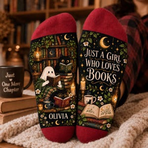 May include: A pair of red and black socks featuring a graphic print of a ghost and black cats reading books in a library setting. The text reads "JUST A GIRL WHO LOVES BOOKS" and "OLIVIA" with illustrations of candles, stars, and a crescent moon.