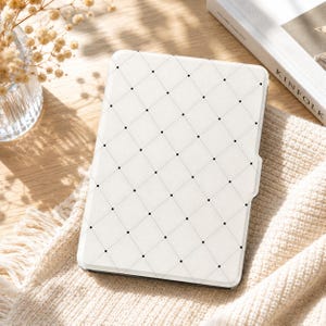 May include: A rectangular e-reader case featuring a white background with a repeating black diamond grid pattern. Each intersection of the thin black lines is marked with a small black dot, creating a clean, geometric design across the surface.