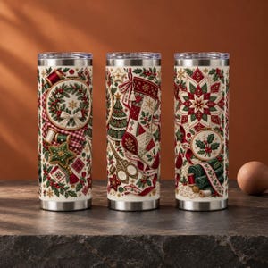 May include: Three cylindrical tumblers with a cream background featuring a festive Christmas craft theme. The designs include embroidered wreaths, stockings, poinsettias, sewing scissors, spools of thread, and holly leaves in red, green, and gold.