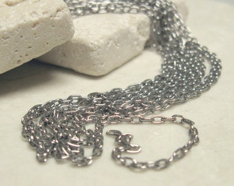 May include: A silver chain necklace with multiple strands of chain links. The chain is lying on a white surface.