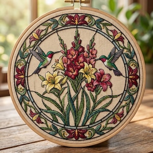 May include: A circular embroidery hoop with a detailed floral design and two hummingbirds. The artwork features red, yellow, and green flowers, with the birds positioned on either side of the central bouquet. The hoop is made of light-coloured wood.