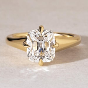 Peut inclure: Une bague en or avec un grand diamant de taille carrée. Le diamant clair est mis en valeur dans un anneau en or poli. La bague présente un design classique et élégant.