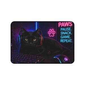 May include: Gaming mousepad featuring a black cat wearing headphones. The mousepad includes a keyboard, mouse, and neon text: "PAWS. PAUSE. SNACK. GAME. REPEAT." A paw print design is also visible.