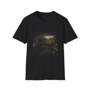 May include: A black short-sleeve t-shirt featuring a graphic print of a black cat sitting in a chair at a desk, facing a computer monitor that displays a landscape scene with a path, trees, and mountains, along with a keyboard and beverage cans.