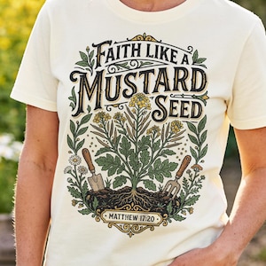 Könnte beinhalten: Ein cremefarbenes Kurzarm-T-Shirt mit einem Grafikdruck einer Senfpflanze, einer Handschaufel und einer Handharke. Der Text "FAITH LIKE A MUSTARD SEED" und "MATTHEW 17:20" ist in einer dekorativen Schriftart mit grünen und gelben Akzenten gehalten.