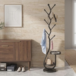 May include: A dark metal coat rack with a tree-like structure featuring multiple branches for hanging items. It includes a circular base, a small integrated shelf with a decorative cutout pattern, and a lower circular tray for storage.