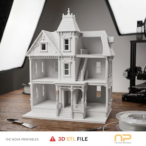 May include: A white 3D printed dollhouse with multiple levels, a front porch, stairs, and detailed window frames. The structure features a central tower with a peaked roof and open rooms. Text at the bottom reads: THE NOVA PRINTABLES 3D STL FILE.