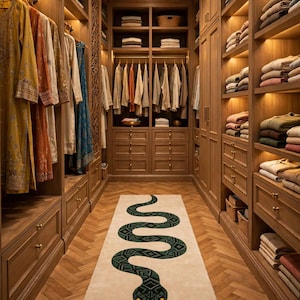 Puede incluir: Una alfombra rectangular que presenta una serpiente verde larga y sinuosa con un patrón geométrico y una lengua roja bífida, centrada sobre un fondo beige claro, colocada en un suelo de madera en espiga dentro de un vestidor con armarios de madera.