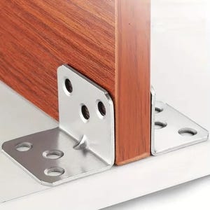 May include: Close-up of two silver metal corner brackets attached to a wooden surface. The brackets are L-shaped with multiple screw holes. The wood has a reddish-brown grain.