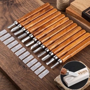 May include: A set of twelve wood carving tools with polished wooden handles and metal blades, each featuring a protective clear plastic cap. The collection includes various blade shapes for detailed woodworking, displayed alongside a small inset image showing a tool carving a curved groove into a light-colored wooden block.