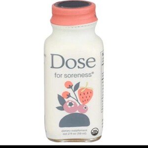 May include: A small clear glass bottle of Dose for soreness dietary supplement with a coral-colored cap. The label features a graphic of a strawberry and berries with the text Dose for soreness and net 2 fl oz (59 ml) and a USDA Organic seal.