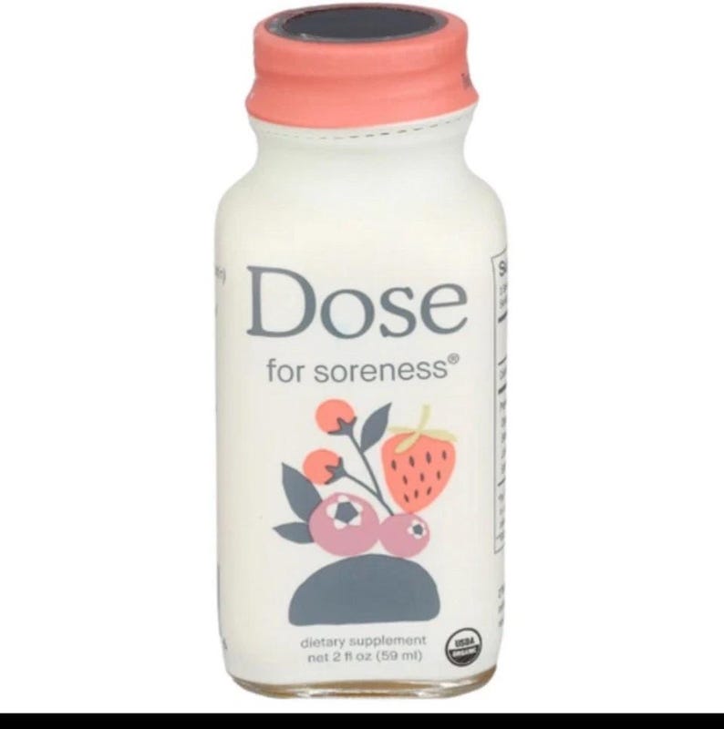May include: A small clear glass bottle of Dose for soreness dietary supplement with a coral-colored cap. The label features a graphic of a strawberry and berries with the text Dose for soreness and net 2 fl oz (59 ml) and a USDA Organic seal.