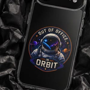 May include: A clear smartphone case featuring a graphic of an astronaut in a space suit with a nebula reflection in the helmet visor. The design includes the text OUT OF OFFICE IN ORBIT, surrounded by planets and stars in blue and orange tones.