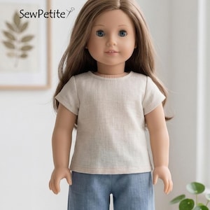 May include: A doll with long brown hair and blue eyes wearing a light beige t-shirt and blue pants. The doll is standing in front of a neutral background. The text "SewPetite" is visible in the upper left corner.