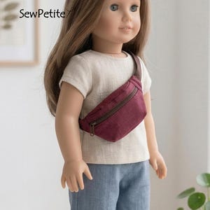 May include: A doll with long brown hair wearing a beige short-sleeved shirt, blue pants, and a dark red fanny pack with a brown zipper. The text SewPetite is visible on the left side. The doll has blue eyes and a neutral expression.