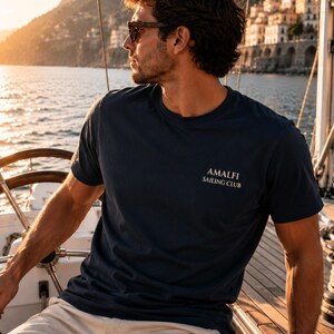 Man wearing Navy Amalfi Sailing Club tee with small front chest logo, styled for Mediterranean vacations, sailing days, and coastal summer outfits.