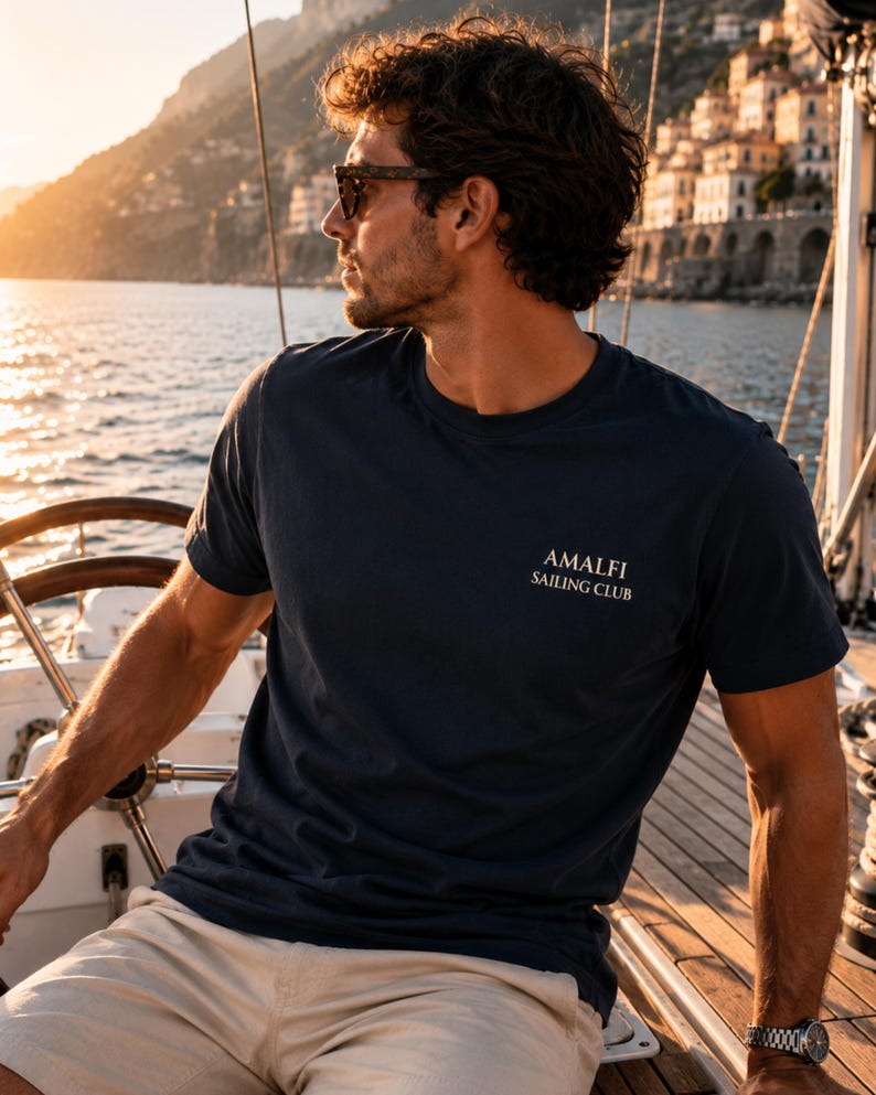 Man wearing Navy Amalfi Sailing Club tee with small front chest logo, styled for Mediterranean vacations, sailing days, and coastal summer outfits.