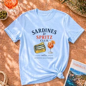 light blue sardines and spritz shirt flatlay, coastal summer tee, sardine graphic shirt, Mediterranean vacation outfit, amalfi shirt, sardegna