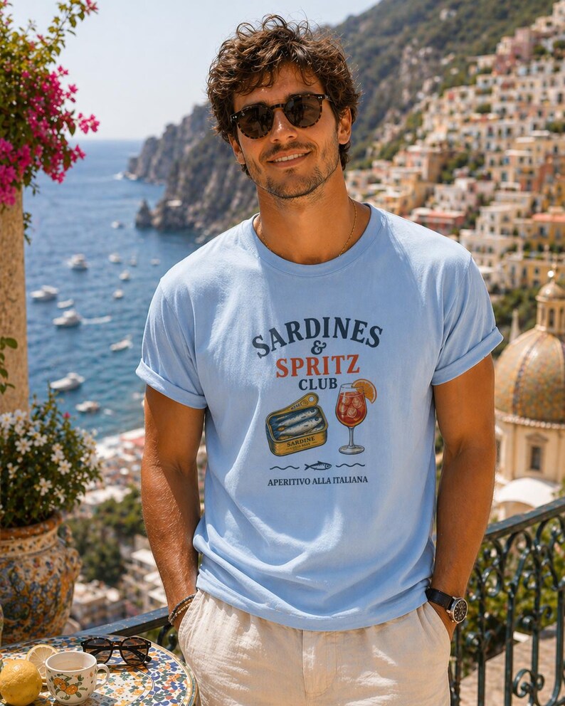 Italian summer shirt mockup on a man in Positano, blue graphic tee with sardines and spritz design, Amalfi Coast vacation outfit, Mediterranean summer fashion