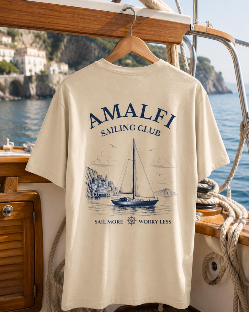 Natural Amalfi Sailing Club shirt hanging on a yacht with large nautical back print, inspired by sailing adventures and Italian coastal escapes.