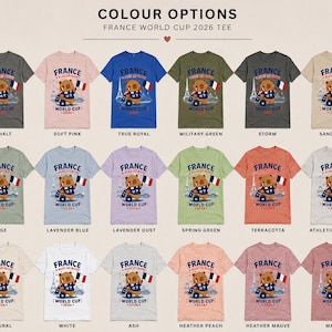 May include: A collection of eighteen t-shirts in various colors, each featuring a graphic of a bear holding a French flag with the text France Allez Les Bleus World Cup 2026. The shirts are displayed in a grid with color names listed below each item.