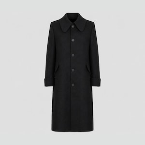 May include: A long black coat featuring a rounded collar, a front button closure with five visible buttons, long sleeves with folded cuffs, and two side pockets with flaps. The coat has a structured silhouette and a solid black color throughout.