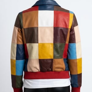 May include: A colorful patchwork leather jacket with a blue collar and red ribbed cuffs. The jacket features a variety of square patches in shades of brown, red, yellow, blue, and white. The back of the jacket is visible.