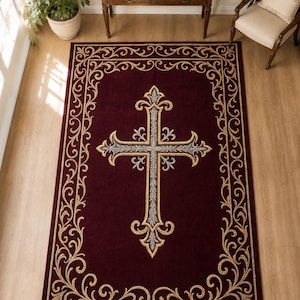 Puede incluir: Alfombra de color burdeos con un gran diseño de cruz ornamentada en el centro. La cruz es plateada y dorada, con adornos detallados. La alfombra tiene un borde dorado con volutas.