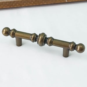 May include: A brass cabinet knob with a decorative design. The knob has a round shape and a smooth finish.