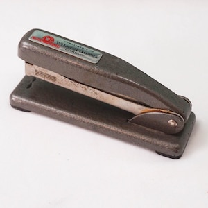 May include: A silver metal stapler with a black base and a label that reads "A subsidiary of Wilson Jones Company".