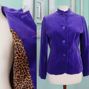 May include: A purple velvet blazer with a leopard print lining. The blazer has a mandarin collar and a button closure.